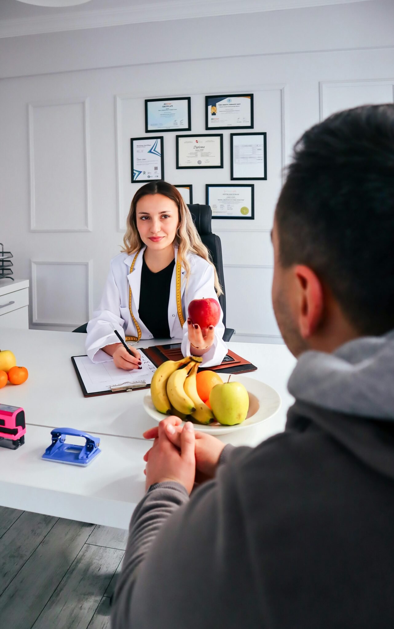 A nutritionist advises a client about healthy eating in a modern office with fruits.